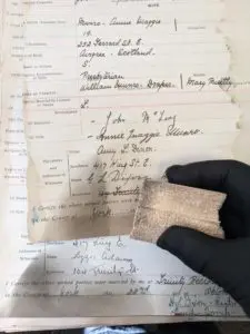 Photograph showing a page of a register with soot damage and special porous rubber sponge used to clean the soot off the page.