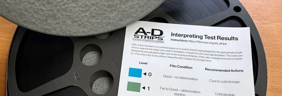 Image showing lid of film canister with title of film, along with 16 mm film reel and bright yellow A-D test strip and result key showing critical deterioration.