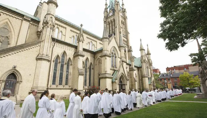 Procession of clergy in white outside St. James Cathedral.