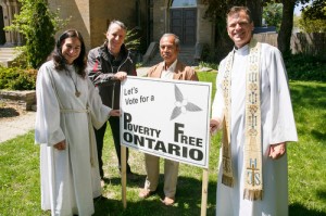 The Rev. Gary van der Meer (right) and pastoral assistant Shauna Cairns Gundy (left) join parishioners as they plant signs on the church lawn. 