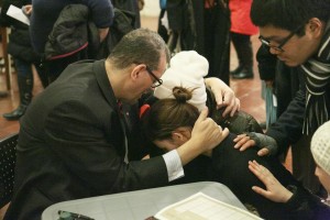 The Rev. Canon Dr. Andrew White prays with two people following the service on Dec. 9.