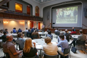 Those attending the symposium watch a presentation. 