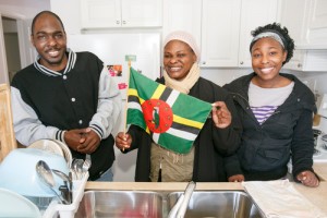Scyrilson, Marianne and Toyan Romain pose with the flag of Dominica in the kitchen of their new home.