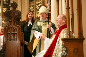 Dean Asbil shakes hands with Archbishop Johnson as he takes his seat. Looking on is Canon Clare Burns. Photo by Michael Hudson 