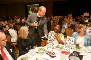 Dean Andrew Asbil refills a guest's wine glass.