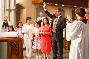 Bachir Brimo and his family acknowledge applause from the congregation at St. Clement's after their baptism. 