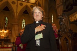 Bishop-elect Riscylla Walsh Shaw stands with her hand over her heart.