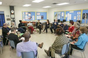 A group of adults sits in a circle as one leads the workshop.