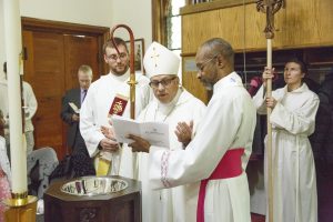 Bishop Fenty prays over the font.