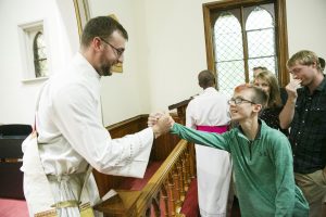 The Rev. Jeff Potter shares the Peace with young parishioner Gareth Davey.